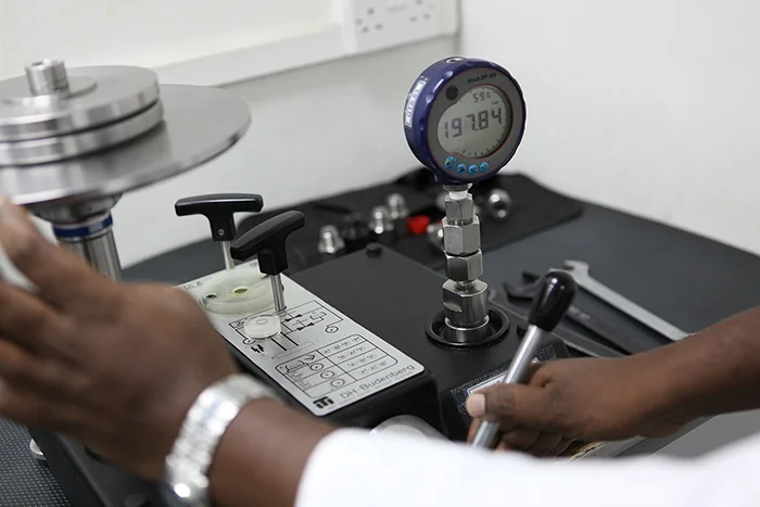 An engineer calibrating a pressure assembly at a laboratory bench